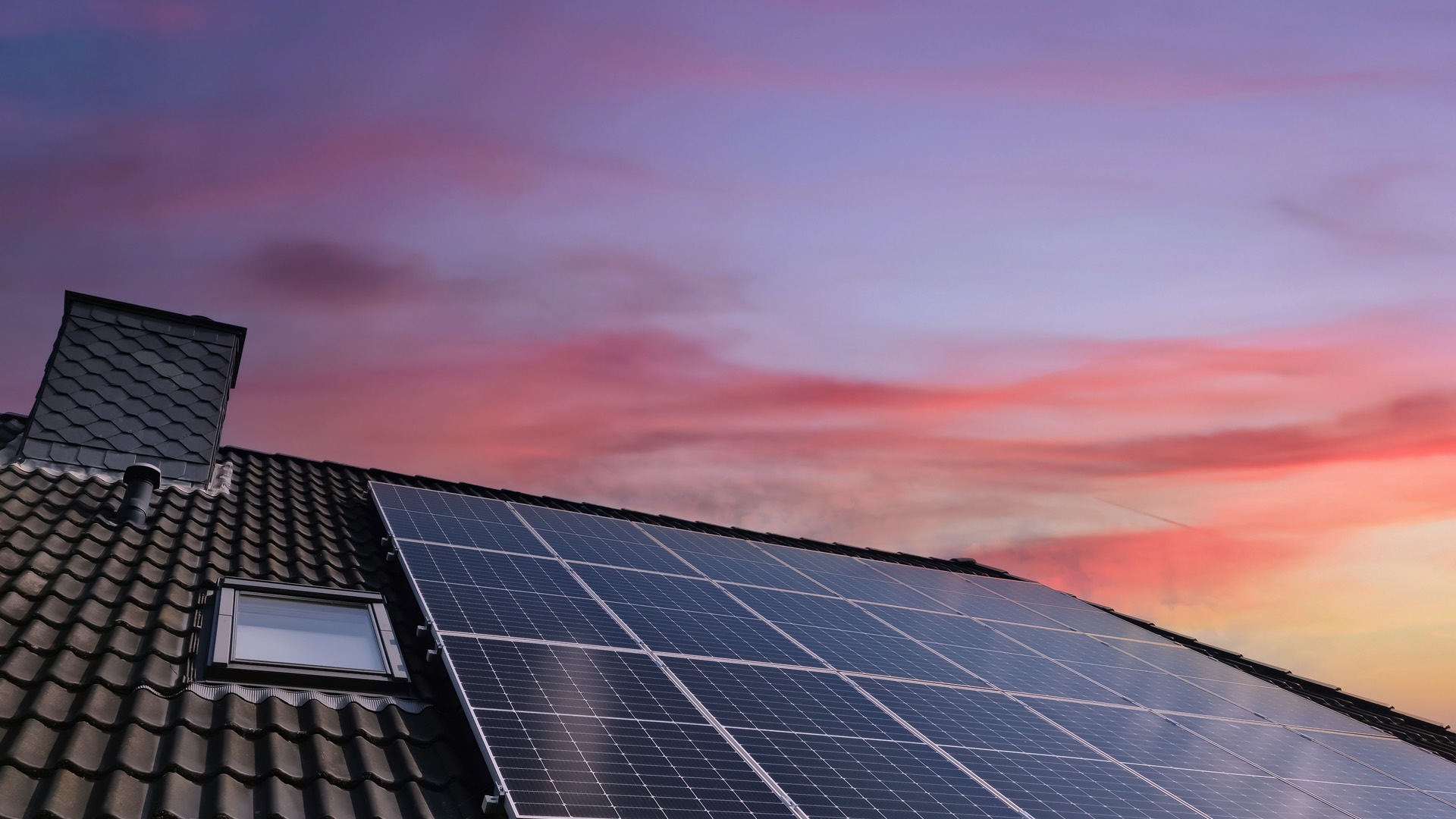 Pannelli fotovoltaici sul tetto di un'abitazione al tramonto, con il cielo rosa